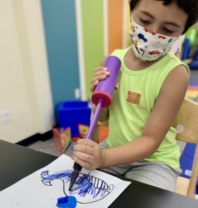 Boy making a whale craft with paper, markers and paint for the water spout.